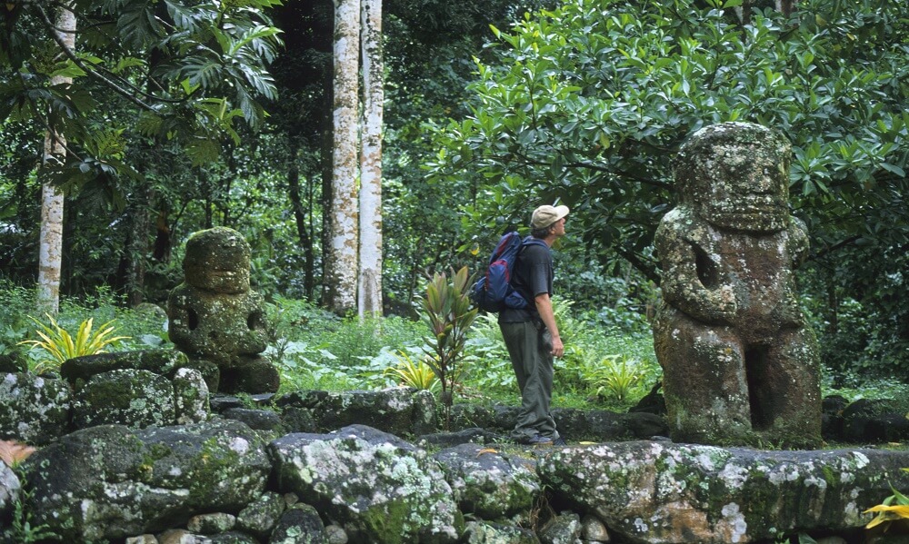 Man viewing stone sculptures in Hiva Oa, French Polynesia