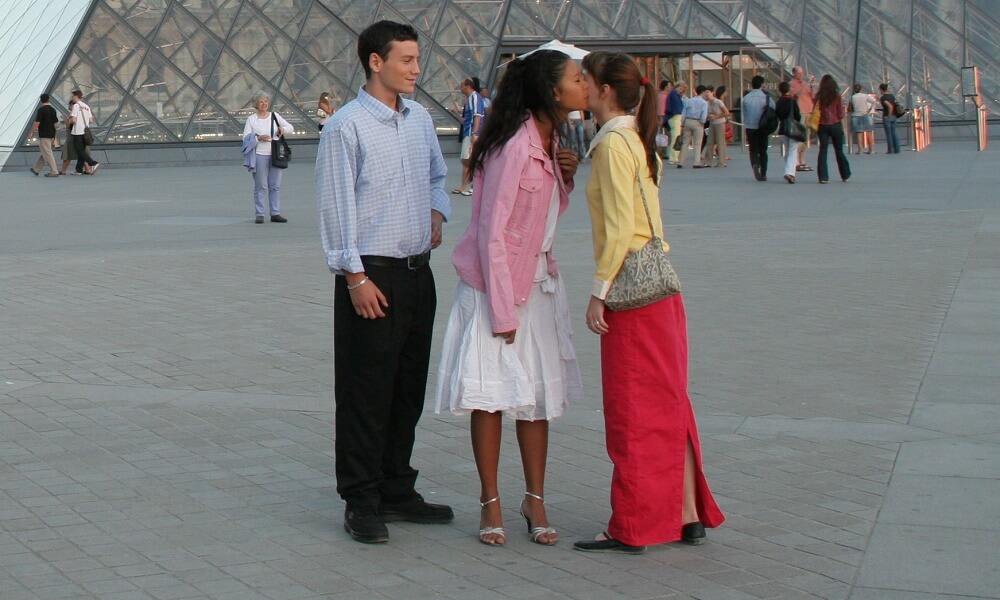 Students shaking hands and kissing in front of the Louvre Museum pyramid, Paris