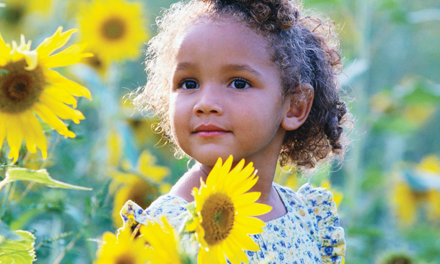 A girl standing in a field of yellow sunflowers.