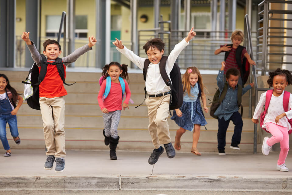A group of energetic elementary school kids leaving school.
