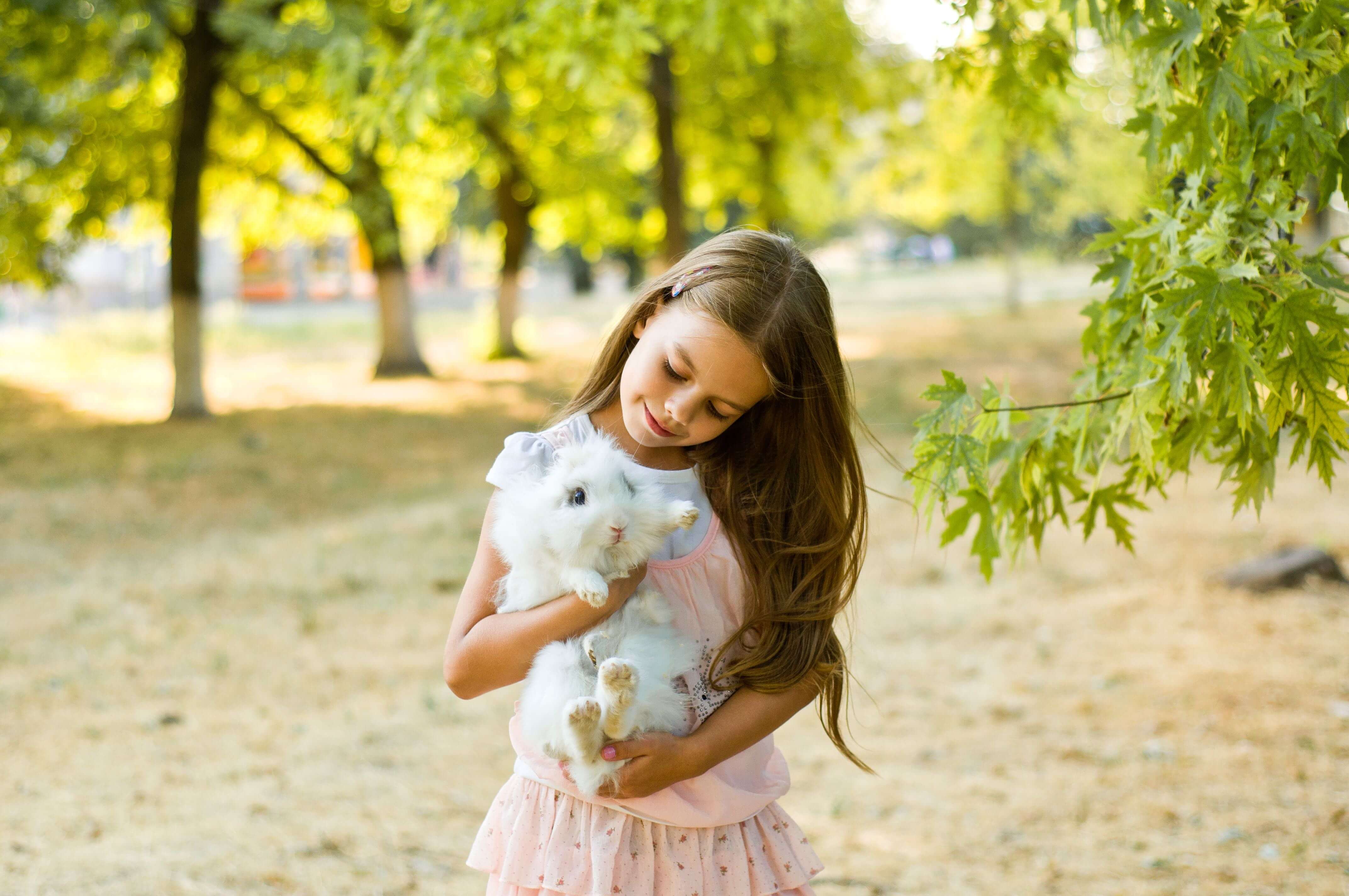 A girl holds a rabbit while walking outside.