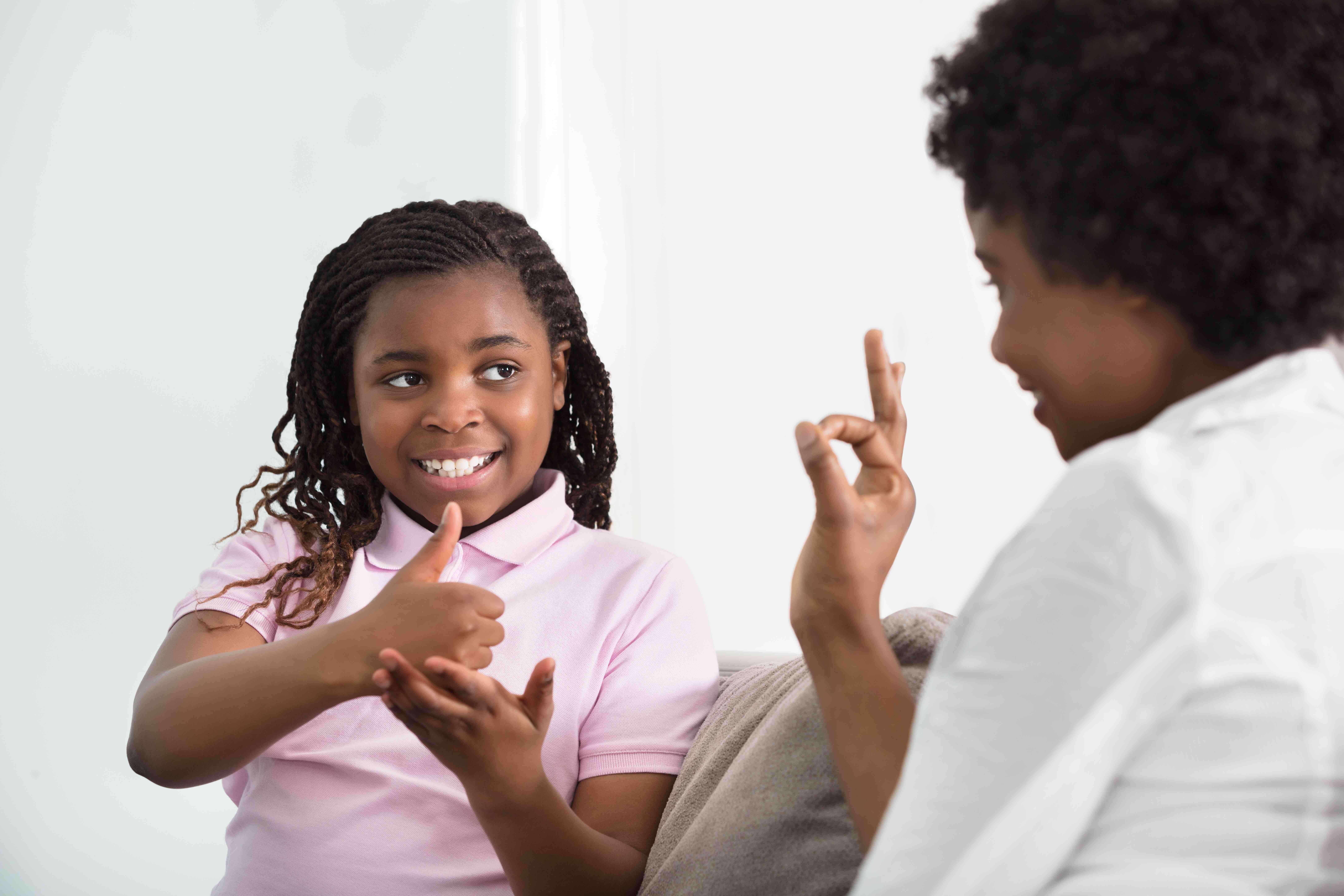 A mother and daughter use sign language to speak with each other.