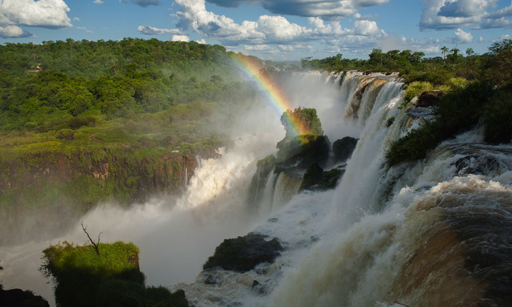 Rainbow appears between a waterfall at Iguazu National Park in Misiones, Argentina