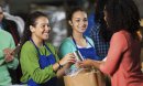 Teen girls volunteering at food bank, receiving donated groceries