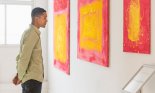 Man looking at paintings in modern art gallery