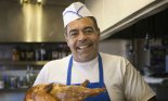 Hispanic male cook holding roast chicken