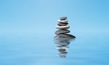 Zen meditation background - balanced stones stack in water with reflection