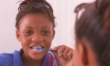 Reflection of a teenage girl brushing her teeth