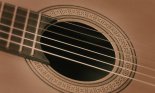Acoustic guitar detail: fretboard, strings, and soundhole