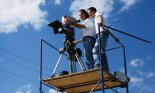 Cameraman and assistant on scaffolding with camera
