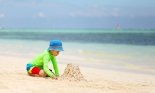 Caucasian boy building a sand castle on a tropical beach