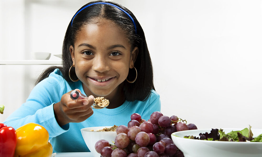 Young black girl (10-11 years old) eating a healthy salad