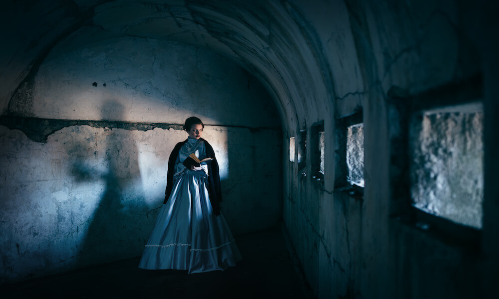 Una mujer vista de estilo victoriano está en una celda. La sombra que se ve en la pared no es la suya.