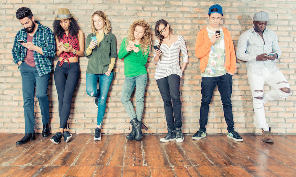 Siete adolescentes miran sus celulares.