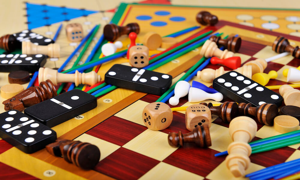 Dominoes, dice, chess pieces and game tokens lying on chess and Chinese checkers boards