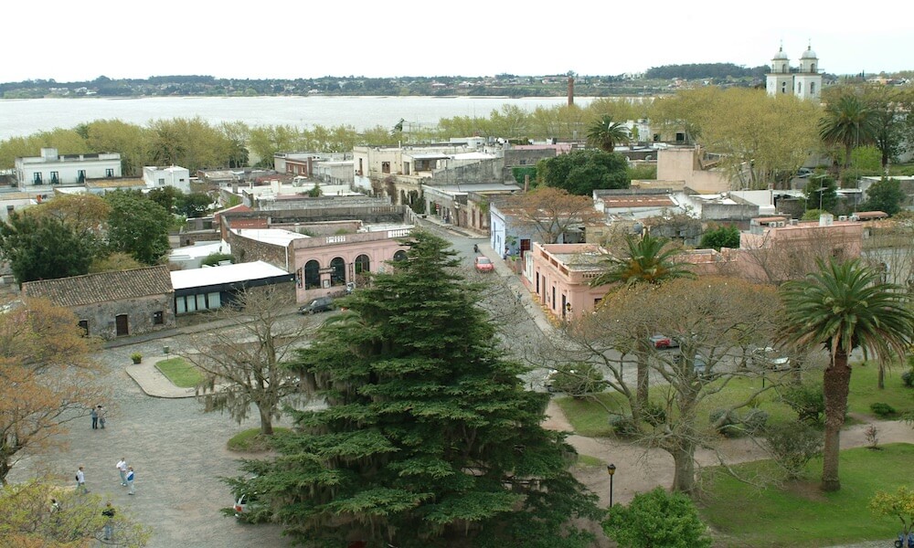 An aerial view of an historic Colonial town with views of a river in the background.