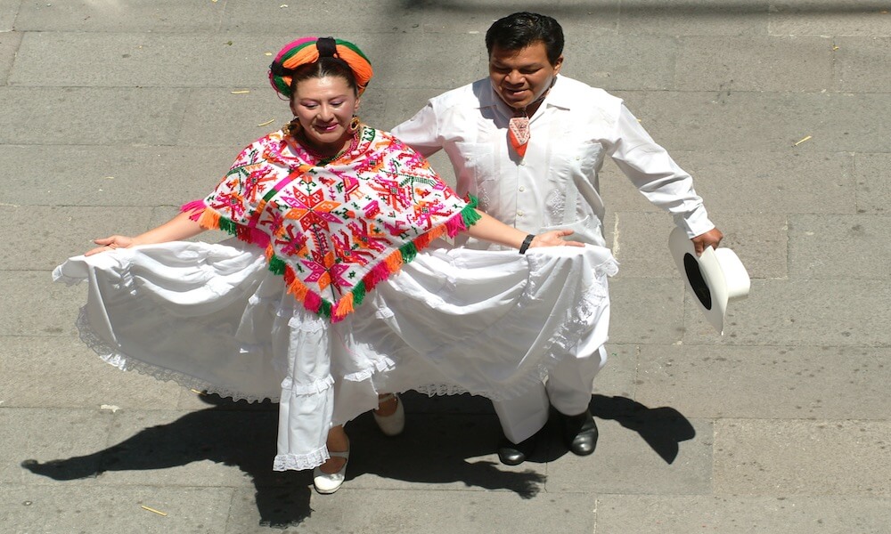 A woman and a man in traditional Mexican garb perform a folkloric dance.