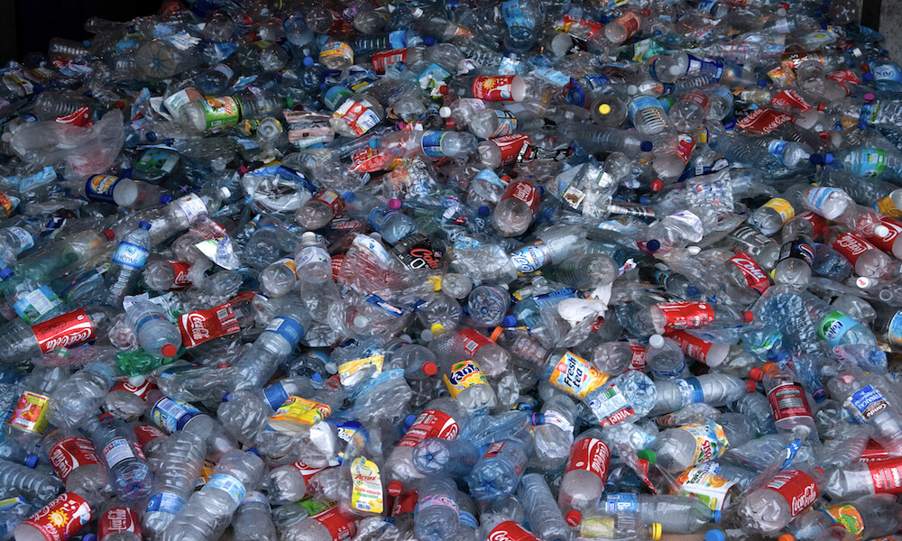 Thousands of clear plastic bottles are piled into a collection container.