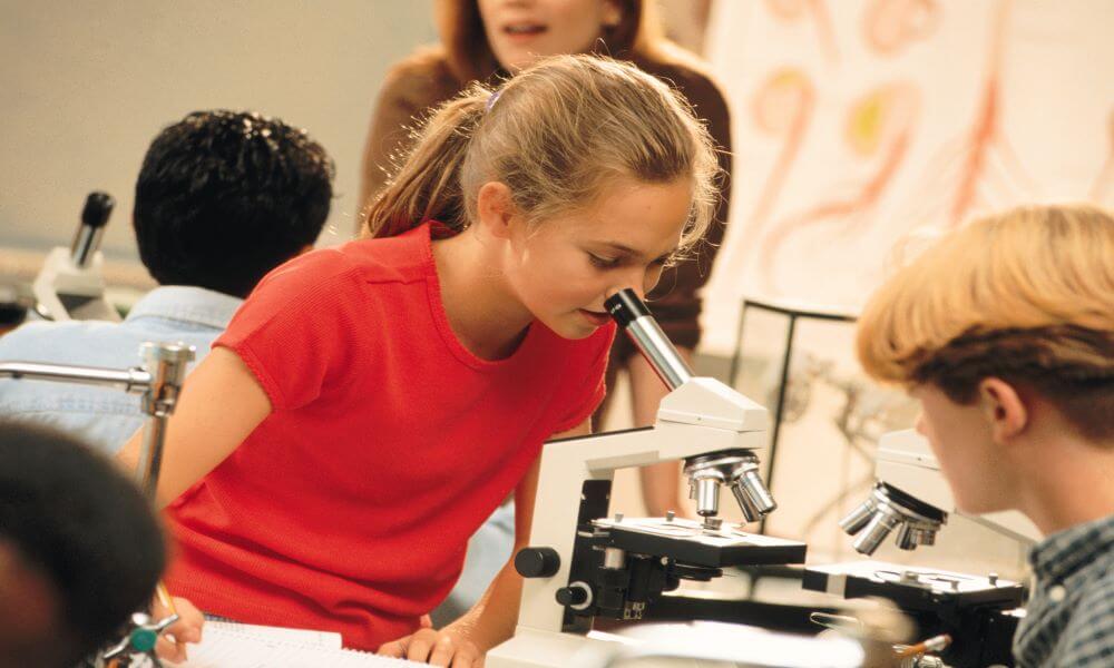 Girl with microscope in science class