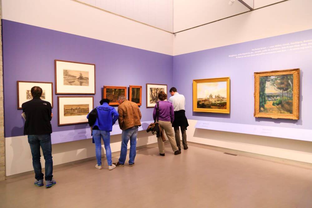 Museum visitors looking at Van Gogh paintings in art gallery