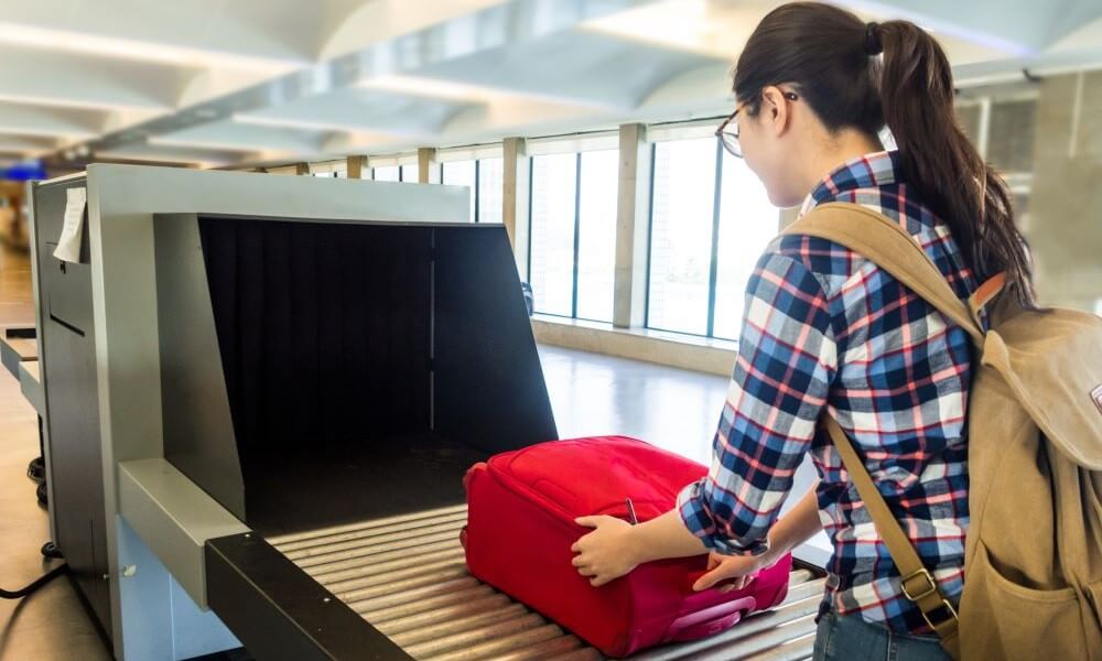 Woman putting luggage on a conveyor belt for airport security screen
