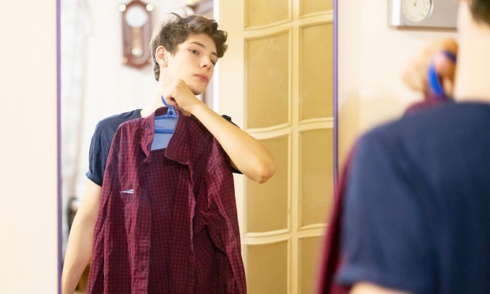 Teenager trying on clothes in front of mirror at home