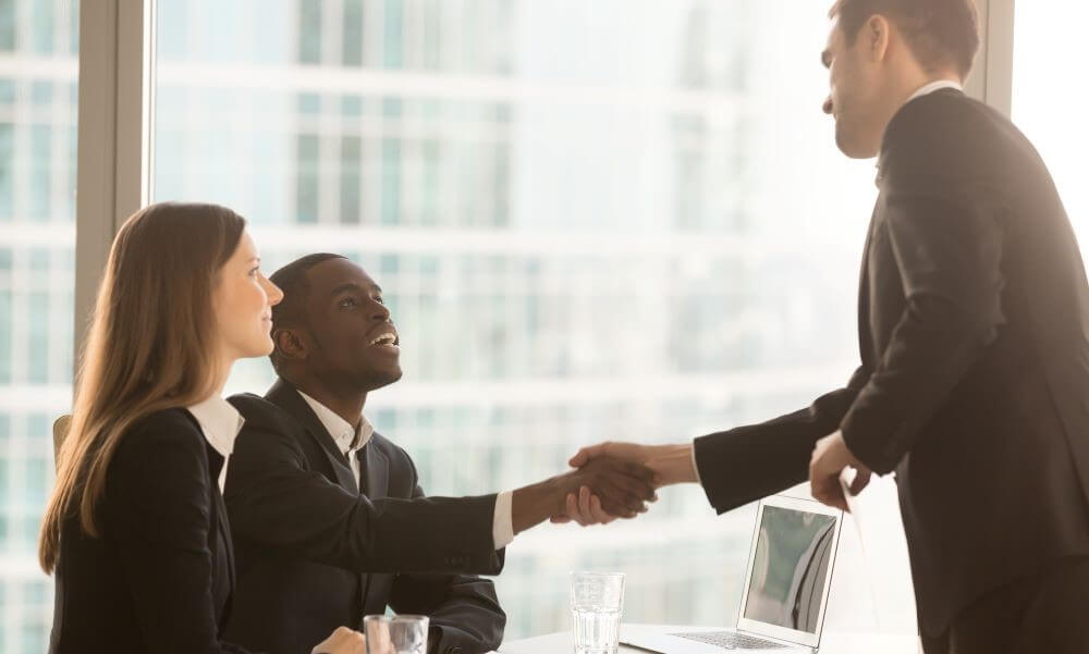 man interviewing for job shaking hands with interviewers