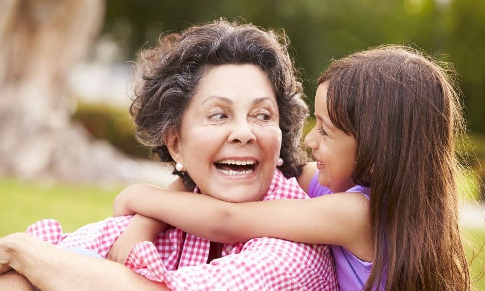 Grandmother And Granddaughter Sitting In Park Together