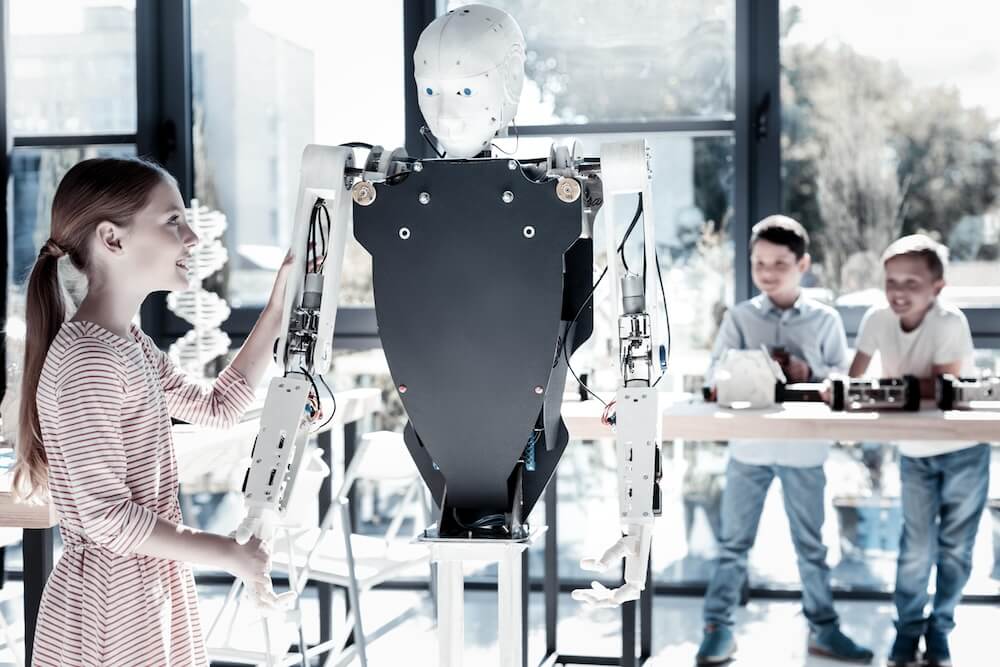Friendly girl shaking hands with human like robot